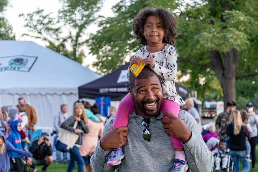 father carrying daughter on shoulders