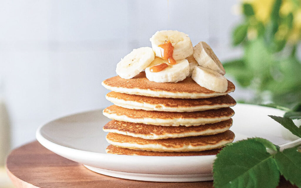 Pancakes on white plate topped with fruits